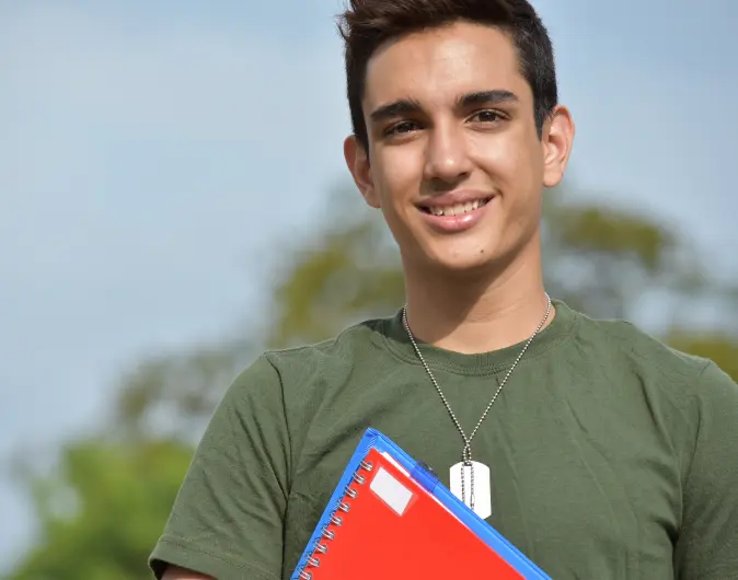 Military student looking at camera holding notebooks