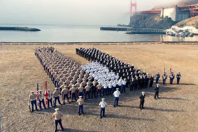 Military personal lined up in formation with the Golden Gate bridge in the background