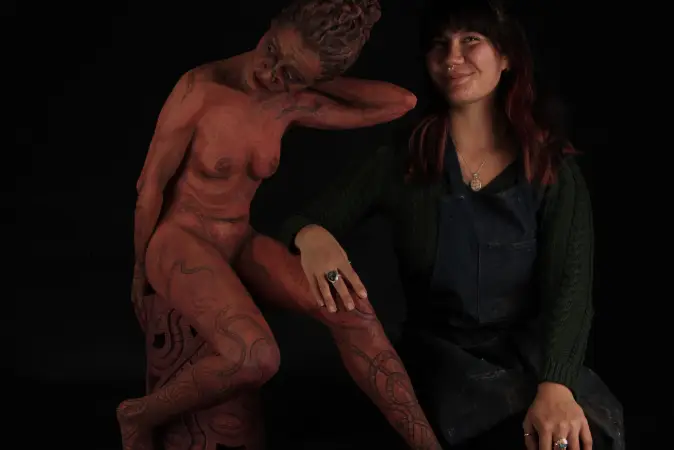 Sculpture student standing next to one of her pieces