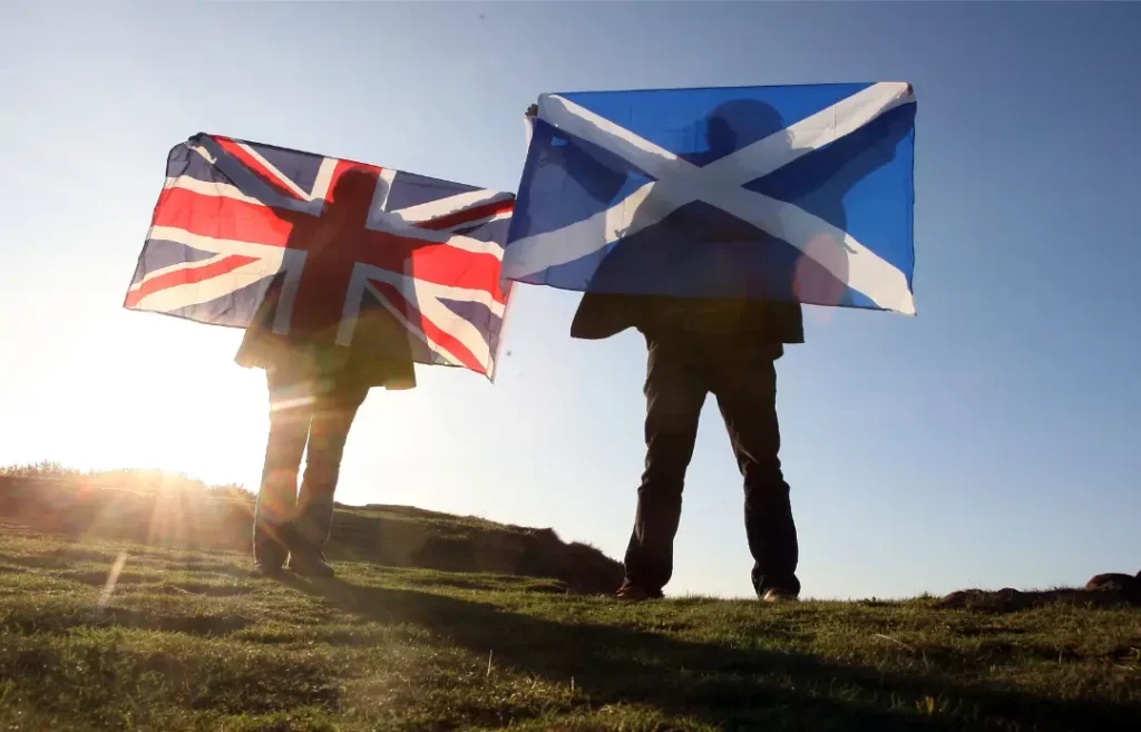 2 people holding the English flag and the Scottish flag