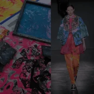 Model walking on runway in colorful fashion attire with abstract art pieces in the background