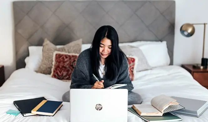 Girl sitting on a bed with a laptop